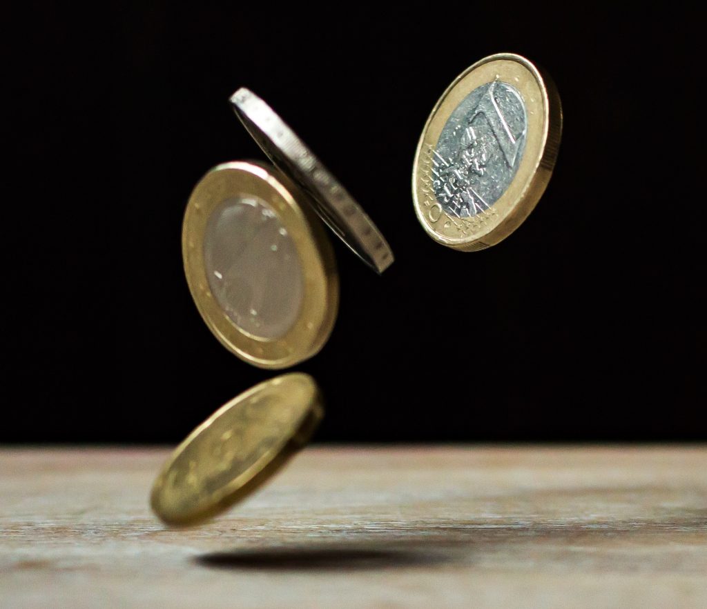 Fallende Euro-Münzen in der Luft, vor dunklem Hintergrund