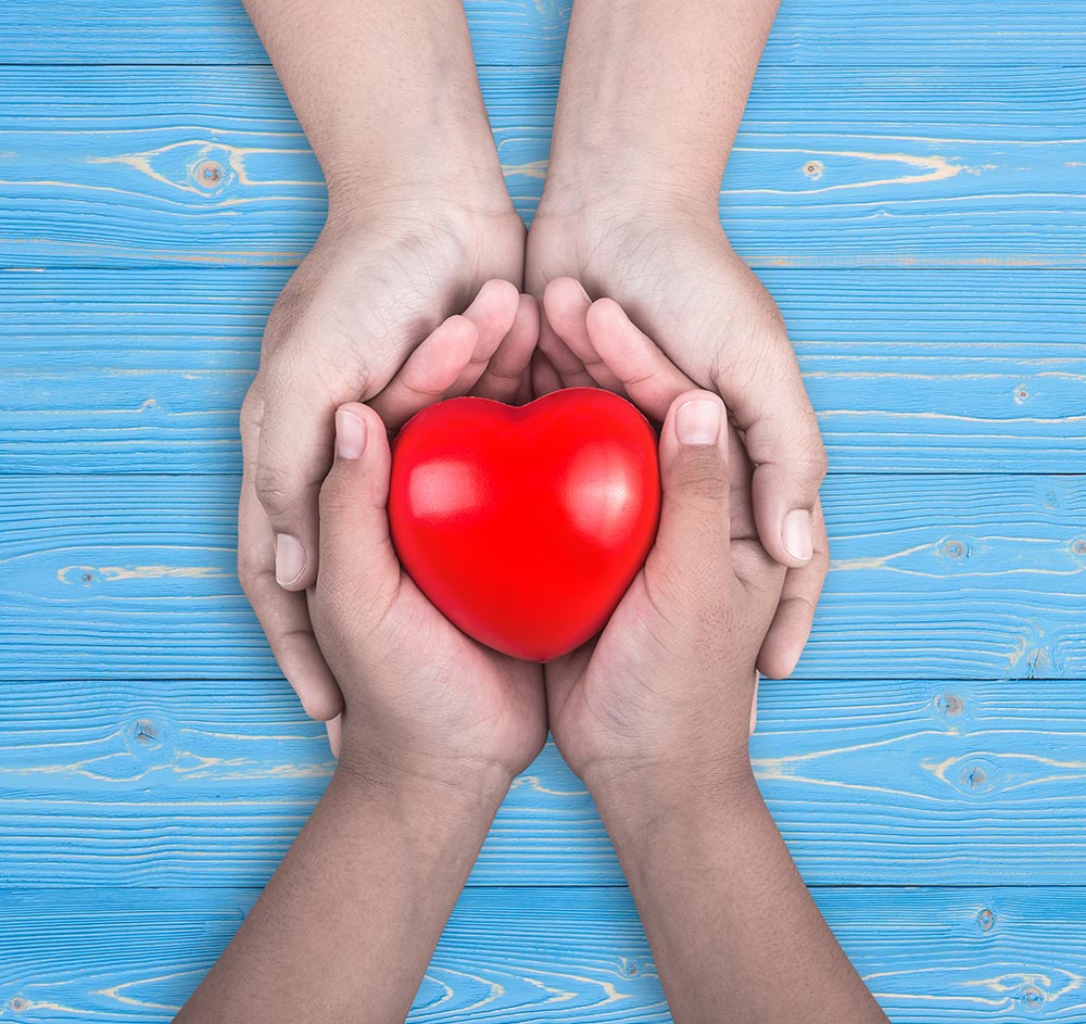 Zwei Personen, die zusammen ein rotes Herz halten.